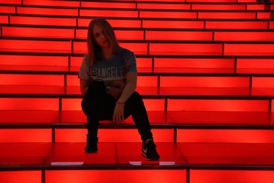 Portrait of woman sitting against red brick wall