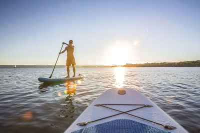 Man with umbrella on boat in sea against sky