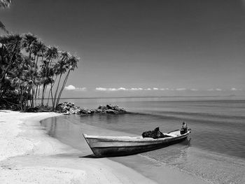 Boat moored on beach against sky