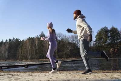 Full length of couple running by lake