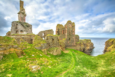 View of abandoned fort by sea against cloudy sky