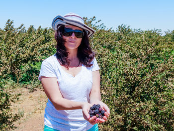 Young woman wearing sunglasses against trees and plants