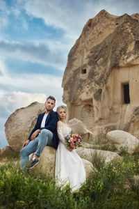 Couple standing on stone wall against sky