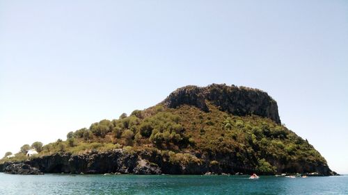 Scenic view of sea and mountain against clear sky during sunny day