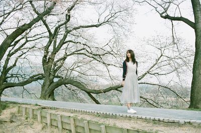 Full length of woman standing on footpath against trees in park