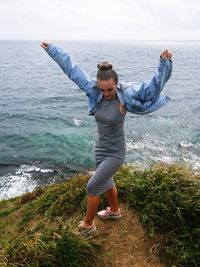 Woman with arms raised standing at beach