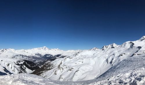 Scenic view of snowcapped mountains against clear blue sky