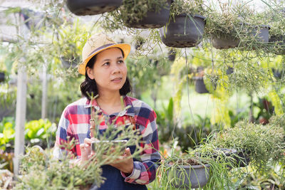 Portrait of woman holding flowers against plants