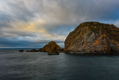 Rock formation by sea against sky