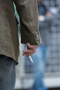 Midsection of man smoking cigarette