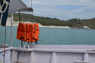 Lifebuoys drying on clothesline by sea against sky