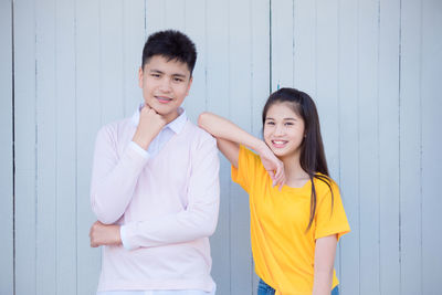 Portrait of smiling boy and girl standing against wall