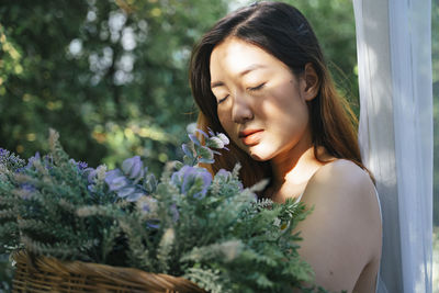 Close-up of beautiful woman holding flowers standing outdoors