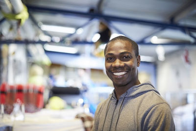 Portrait of smiling mid adult male volunteer standing in illuminated warehouse