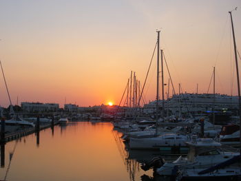 Sailboats in sea at sunset