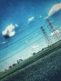 Low angle view of electricity pylon against cloudy sky