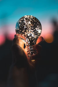 Close-up of hand holding illuminated light bulb