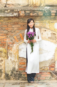 Young woman standing against wall