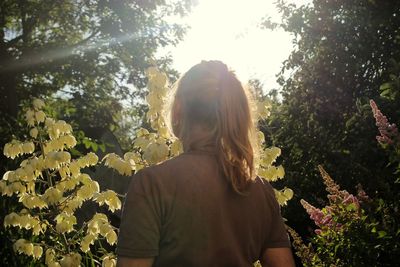 Rear view of woman standing by flowering plants