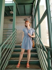 Full length portrait of woman standing on staircase