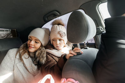 Mother and daughter in the car in warm clothes go on vacation person