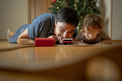 Happy father and son playing with toy train at home