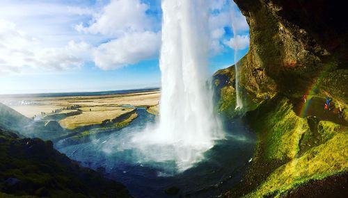 View of waterfall against cloudy sky