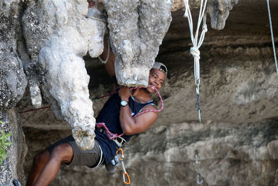 Young man hanging on rock