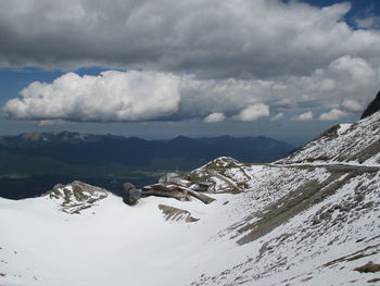 Scenic view of snow covered mountains against cloudy sky