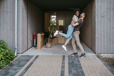 Happy multiracial couple having fun while standing at building entrance