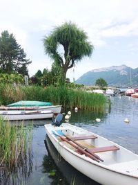 Boats moored in swimming pool by lake against sky