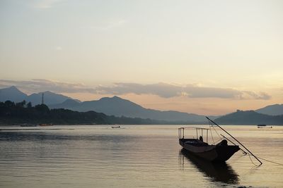 Boat moored on sea against sky during sunset