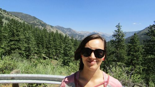 Portrait of smiling beautiful woman wearing sunglasses against sawtooth mountains