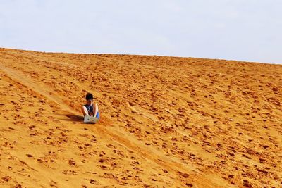 Woman on sand dune against clear sky