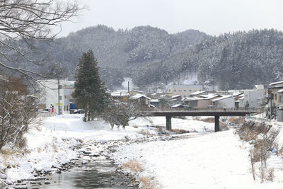 Snow covered houses by buildings in city