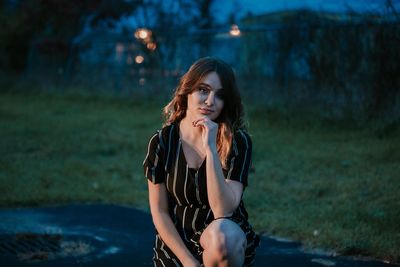 Young woman wearing sunglasses against trees at night