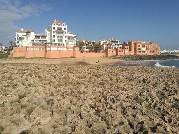 Beach by buildings against sky in city