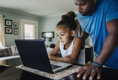 Father and daughter using laptop at home