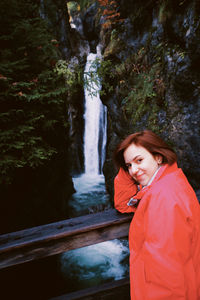 Portrait of woman standing against waterfall