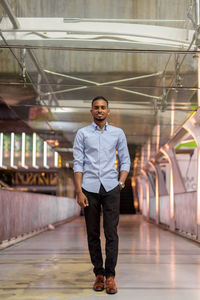 Handsome black african businessman walking outdoors in city at night standing at footbridge