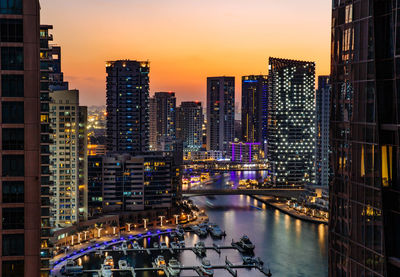 Illuminated buildings in city against sky at sunset