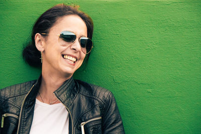 Portrait of smiling young woman against green wall