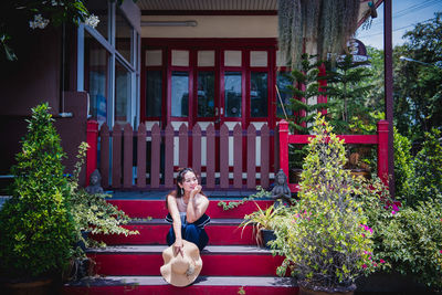 Portrait of woman sitting outside house