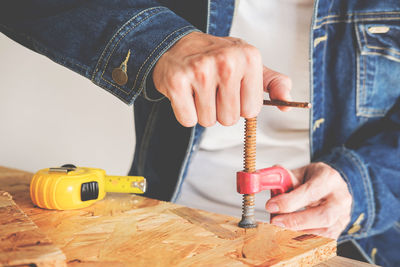 Midsection of man using clamp on wood