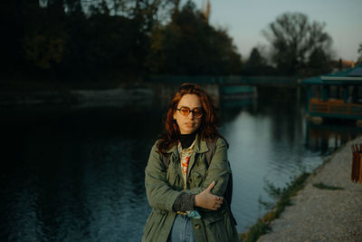 Portrait of young woman standing by lake