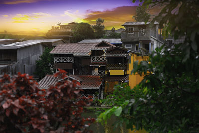 Houses and trees against sky during sunset