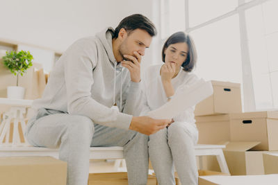 Couple reading document while sitting on table