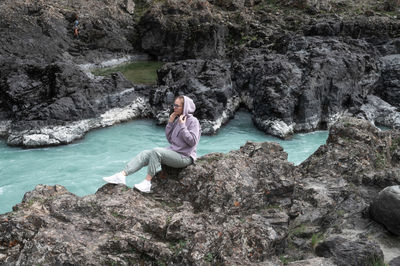 Rear view of woman sitting on rock