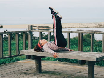 Portrait of woman sitting on bench against sky