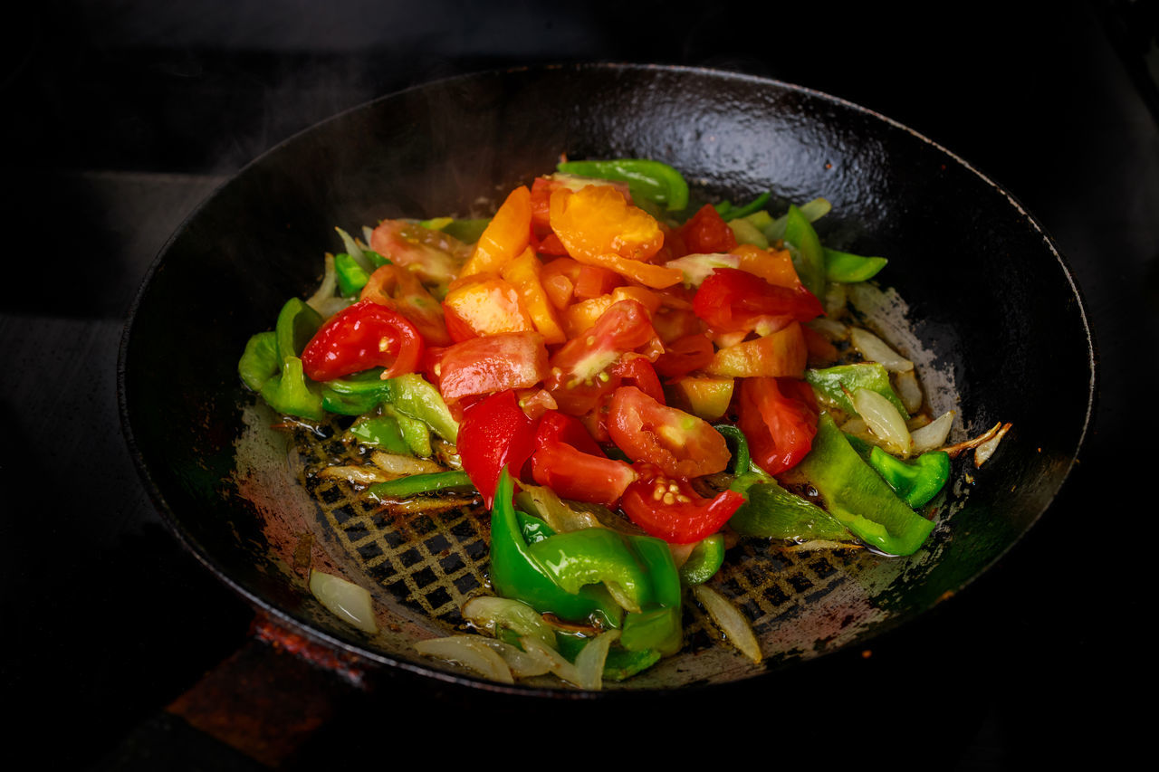 food and drink, food, healthy eating, vegetable, wellbeing, freshness, wok, dish, indoors, kitchen utensil, produce, pepper, fruit, cooking pan, household equipment, no people, bell pepper, black background, salad, meal, tomato, cuisine, meat, spice, dark, high angle view, studio shot, pan, stir-fried, close-up